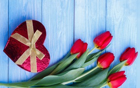Букет красных тюльпанов на синем фоне с подарком в форме сердца