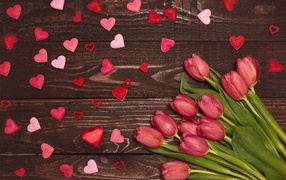 Bouquet of tulips on a wooden background with hearts