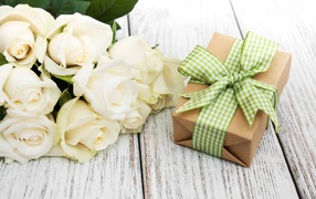 Bouquet of white roses on a table with a gift