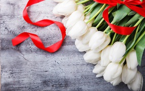 Букет белых тюльпанов с красным бантом на сером столе