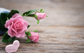 Розовые искусственные розы с сердцем на деревянном фоне