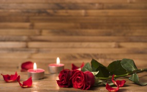 Two red roses on the table with candles