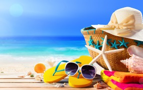 Сумка, шляпа, очки, сланцы и полотенце на пляже с ракушками летом