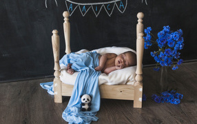 A baby is sleeping on a wooden bed.