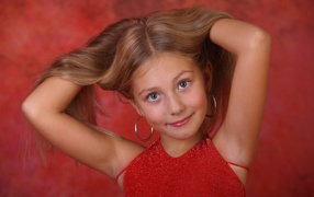 Красивая маленькая девочка с руками в волосах
