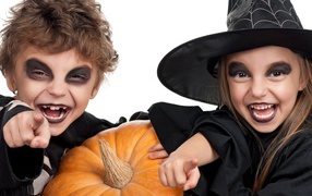 Мальчик и девочка с тыквой на белом фоне в костюмах на Хэллоуин 