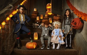 Дети в костюмах на Хэллоуин с тыквами на ступеньках