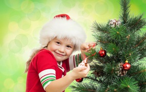 Маленькая красивая девочка наряжает елку на новый год