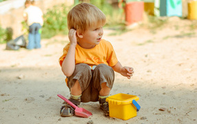 Маленький мальчик играет на песке 
