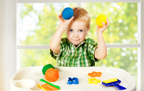 Маленький мальчик играет с игрушками у окна