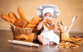 Маленький мальчик с хлебобулочными изделиями на столе 