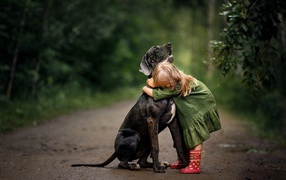 Little girl hugs a big black dog