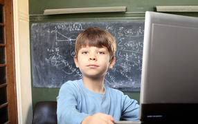 Мальчик школьник делает уроки за ноутбуком