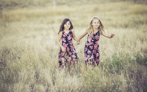 Две маленькие девочки бегут по траве