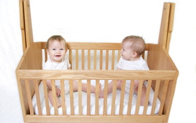 Two smiling babies in a wooden crib