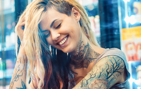 Улыбающаяся девушка с татуировками на теле