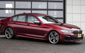 Красный автомобиль BMW M550i XDrive, 2021 года у гаража