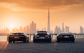 Три автомобиля  Bugatti Veyron и Bugatti Chiron на фоне заката