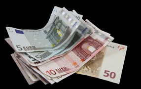 Много бумажных купюр евро на черном фоне