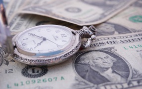 Карманные часы и доллары лежат на столе 