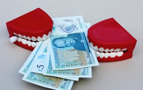 Два держателя денег в форме челюсти с купюрами на сером фоне
