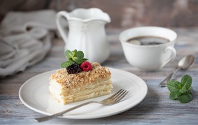 Кусок торта лежит на белой тарелке на столе с кофе