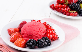 Шарик фруктового мороженого с ягодами на белой тарелке