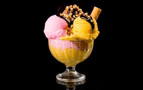 Шарики фруктового мороженого в креманке с орехами и шоколадом на черном фоне