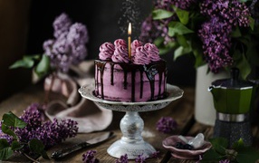 Berry cake with a candle on a table with lilacs