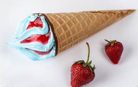 Рожок с голубым мороженым на сером фоне с клубникой 
