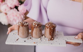 Chocolate dessert in jars in the hands of a girl