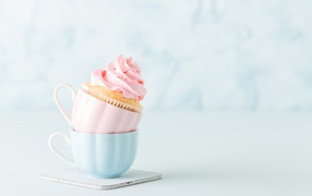 Cupcake with pink cream with cups on the table