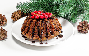 Вкусный кекс с шоколадом и красной смородиной на столе с еловой веткой и шишками