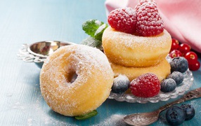 Вкусные пышные пончики с ягодами черники и малины с сахарной пудрой 