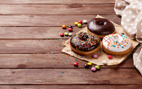 Пончики с глазурью на столе с конфетами на деревянном столе