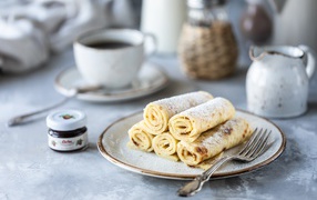 Pancakes on a plate with icing sugar on a table with coffee