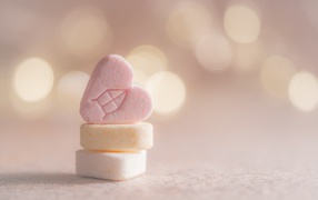 Small heart shaped candies on pink background