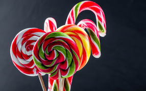 Вкусные разноцветные конфеты на палочке на сером фоне