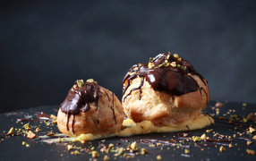 Two choux pastries with chocolate on a gray background