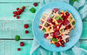 Appetizing waffles with raspberries, red currants and jam