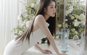 A beautiful Asian girl in a white dress stands at the mirror