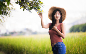 Девушка азиатка в шляпе на поле 