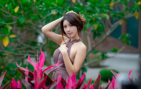 Красивая девушка азиатка в платье у красных цветов