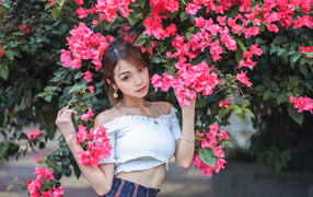 Красивая азиатка стоит у дерева с красными цветами