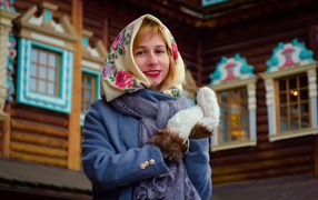 Beautiful Russian woman in a headscarf stands at the house