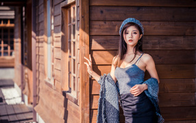 Красивая девушка азиатка стоит у деревянной стены 