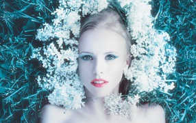 Красивая голубоглазая девушка на траве с белыми цветами