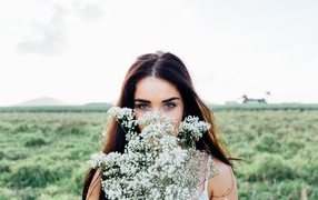 Красивая кареглазая девушка с букетом белых полевых цветов 