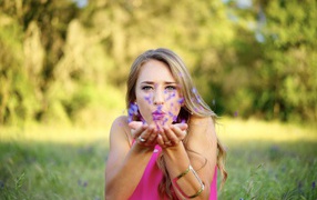 Beautiful girl blows petals from her palms