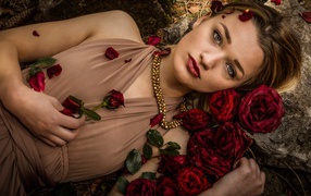 Красивая девушка в платье лежит на земле с розами